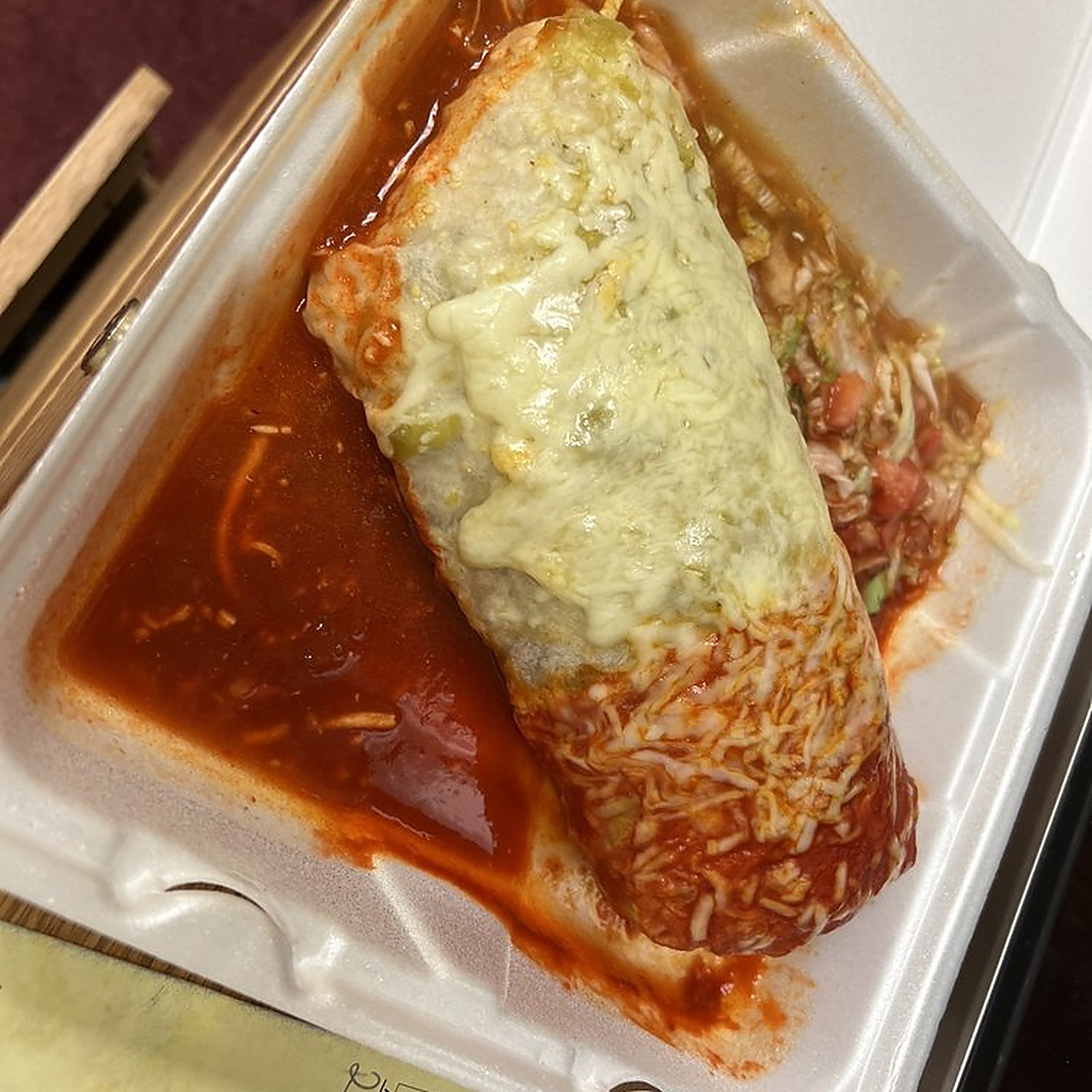 A burrito under red sauce and melted cheese